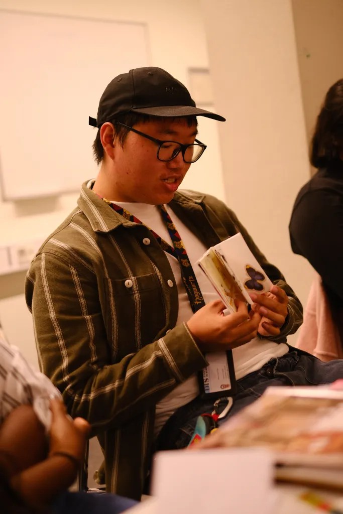 A male student shows his zine to his peers.